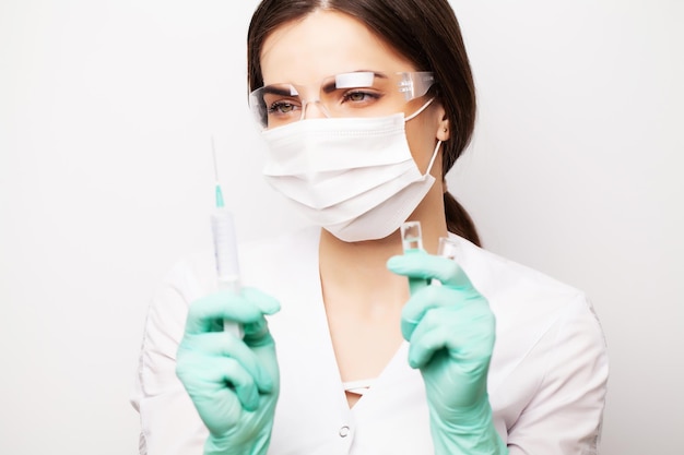 Woman doctor in medical mask picks up syringe to give an injection