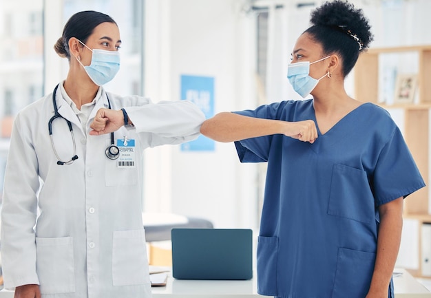 Woman doctor and nurse in a hospital elbow greeting in surgical mask during the covid pandemic Teamwork healthcare worker and medical professional with protection from virus during consultation