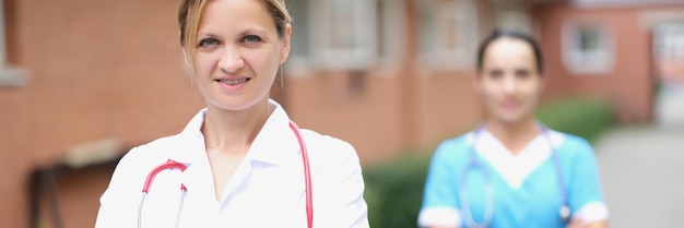 Woman doctor and nurse stand near the clinic