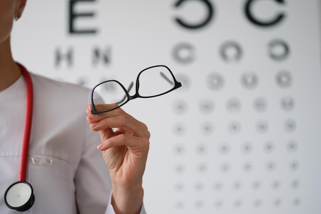 Woman doctor ophthalmologist shows glasses closeup blurry