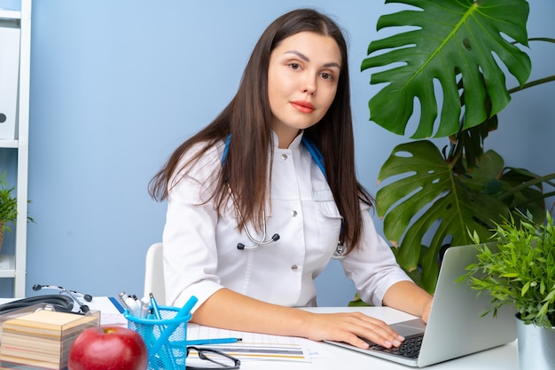 Woman doctor portrait at her office desk, office interior