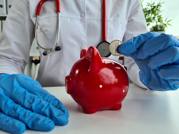 Woman doctor put coin in piggy bank closeup