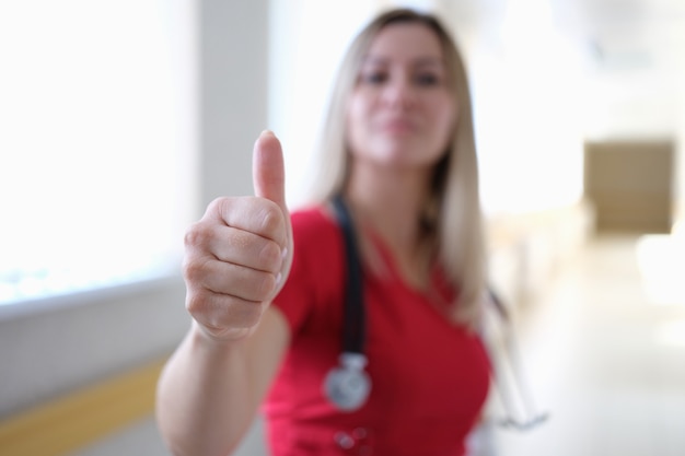 Woman doctor in red uniform showing thumb up closeup