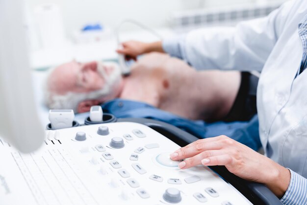 Woman doctor scanning vessels on the neck with ultrasound\
device scan selective focus