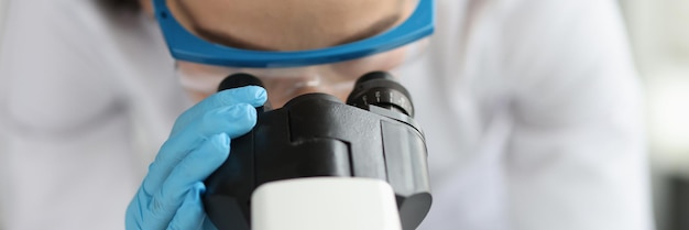 写真 実験室の概念の臨床マクロ研究で顕微鏡を通して見ている女性医師の科学者