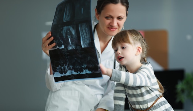 Photo woman doctor showing little girl xray in clinic