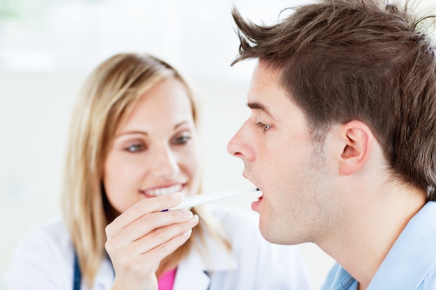 Woman doctor taking the temperature of her patient