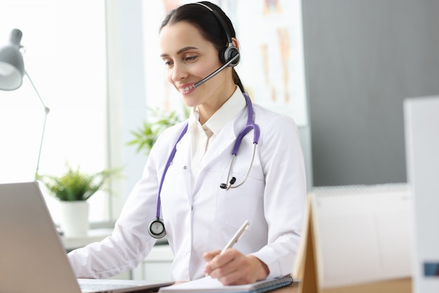 Woman doctor with headset looking into laptop screen. Psychological help online concept