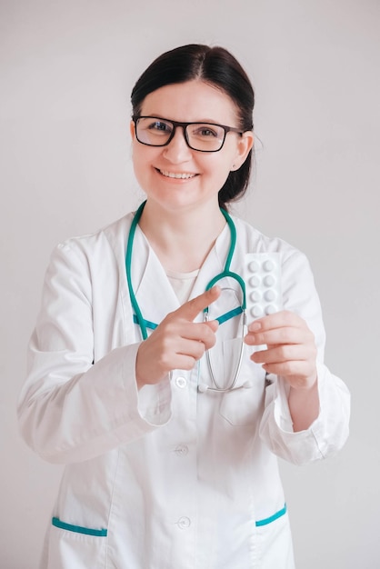 Женщина-врач с таблетками в руках на белом фоне