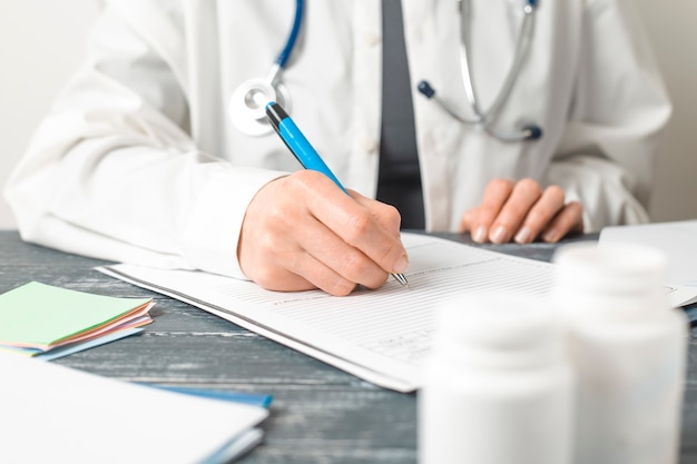 Woman doctor writes a medical report in the office of the clinic. 