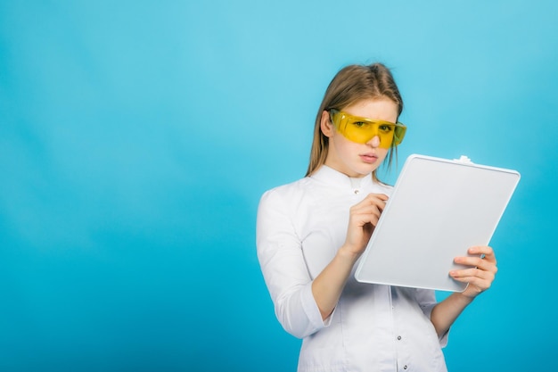 Woman doctor in yellow glasses and desk on blue background