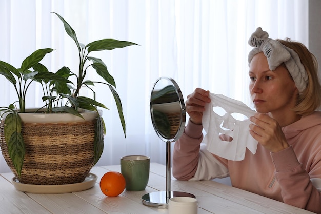 A woman does cosmetic procedures in front of a mirror