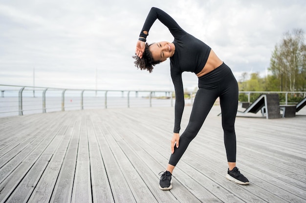 Foto una donna fa esercizi di fitness usa un tracker in mano un orologio intelligente per l'allenamento sportivo in abbigliamento sportivo