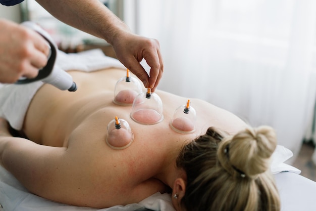 Una donna fa un massaggio all'anca con un barattolo sottovuoto per un massaggio anticellulite.