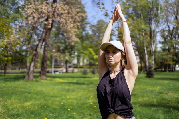 女性が公園でヨガのアーサナ ポーズ トレーニングを行います 身体の調和とバランスはマットを使用します