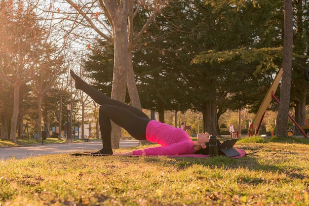 La donna fa esercizi di yoga in un parco al tramonto