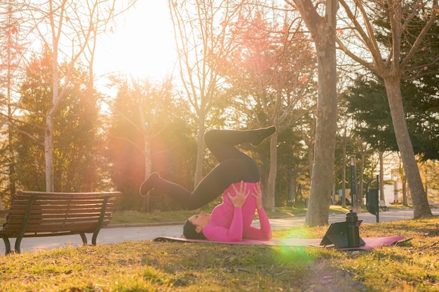 Woman does yoga exercises in a park at sunset