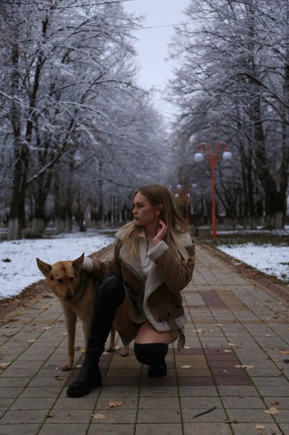 a woman and a dog are on a sidewalk in the snow