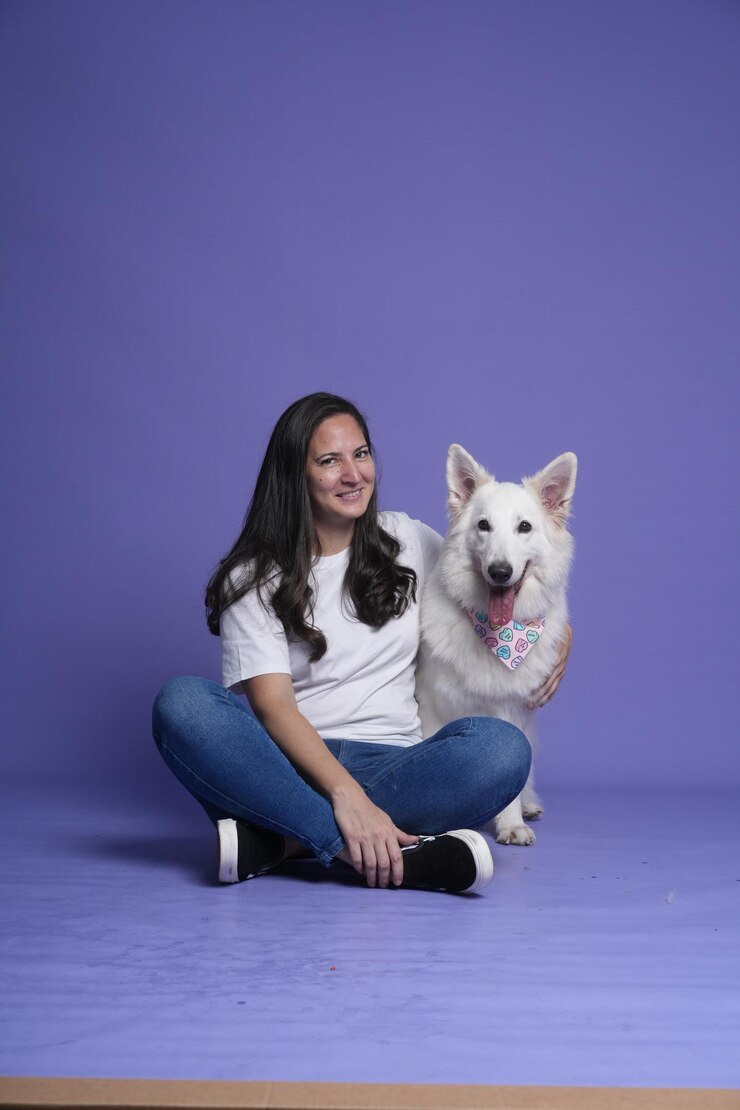 a woman and a dog are sitting on a purple wall