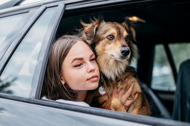 Foto donna e cane che guardano attraverso il finestrino della macchina