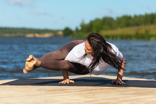 Photo a woman doing ashtavakrasana exercise balance asana handstand training in sportswear