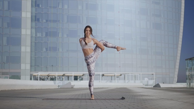 Woman doing bird of paradise pose in city Yoga trainer balancing on one leg