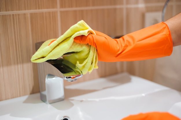 Woman doing chores in bathroom, cleaning tap.