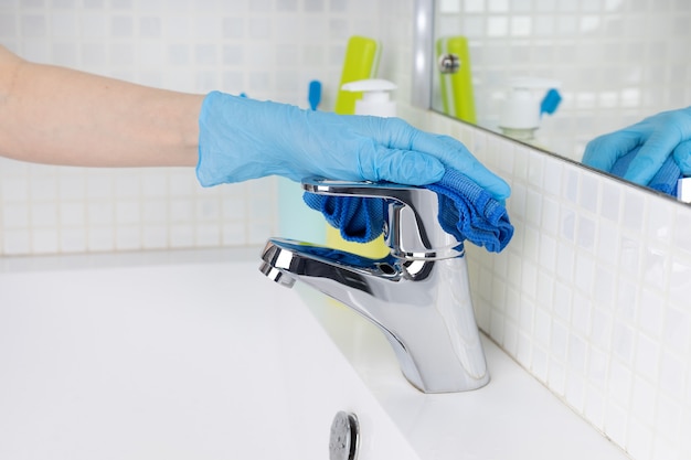 Woman doing chores in bathroom cleaning of water tap