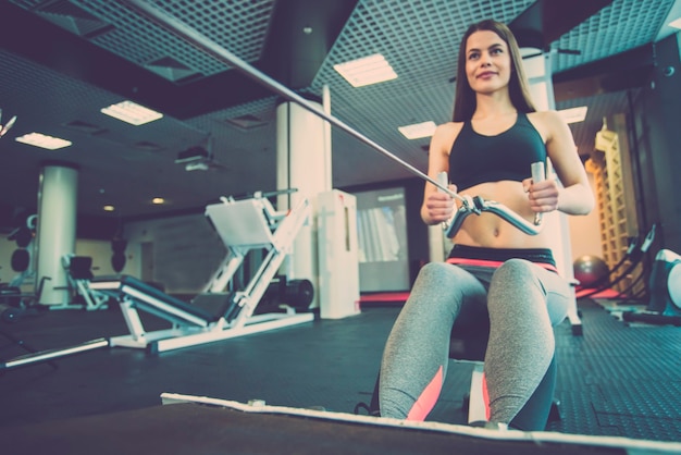 Женщина делает упражнения на оборудовании фитнес-центра