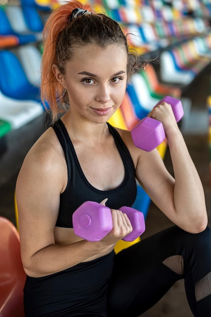 Woman doing exercises on colored chairs in the stadium