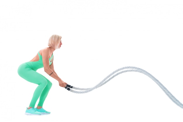 Woman doing exercises with battle rope on white