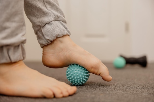 Woman doing flatfoot correction gymnastic exercise using massage ball Myofascial relaxation of foot muscles Hallux valgus Pain Identification of flat feet Self care practices at home healthcare