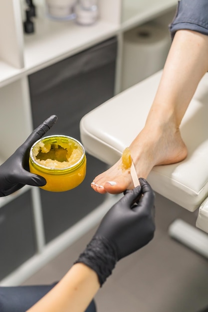 Woman doing foot peeling in pedicure spa salon sugar scrub and relax beauty procedure