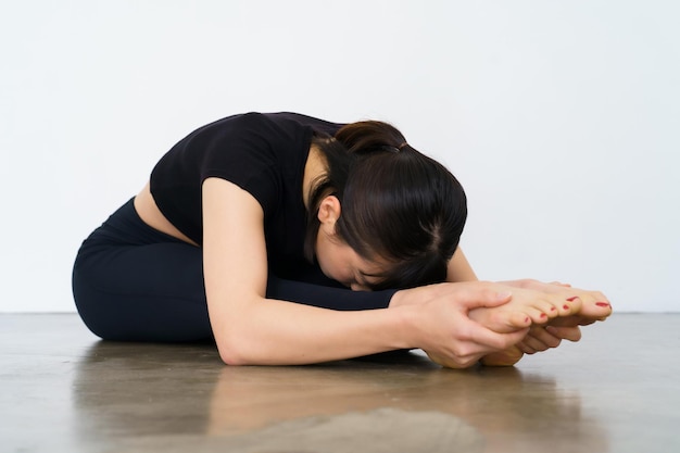 A woman doing a forward bending exercise indoors