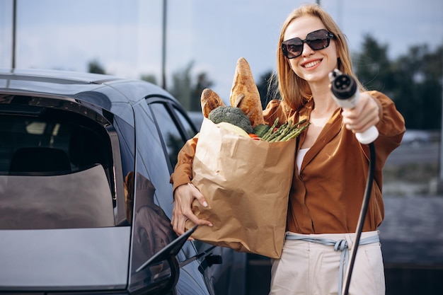 woman doing grocery shopping while electric car charging