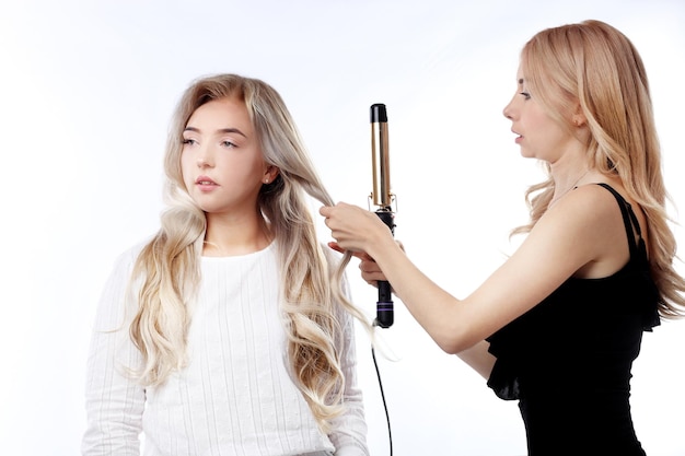 Woman doing hairstyle with hair straightener isolated on white