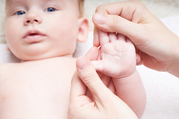 Woman doing hand massage to baby On light