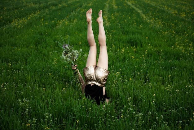 陸上の植物の間でヘッドスタンドをしている女性