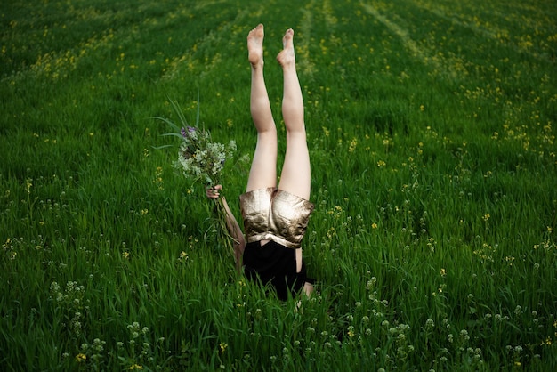 Foto donna che fa il headstand in mezzo alle piante sulla terraferma