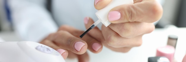 Woman doing her own manicure with pink nail polish closeup manicure training concept