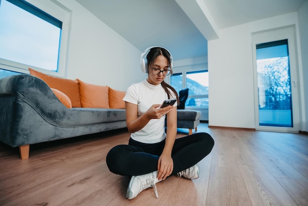 Женщина, занимающаяся дома с наушниками и смартфоном для видеозвонка, отражает современный образ жизни