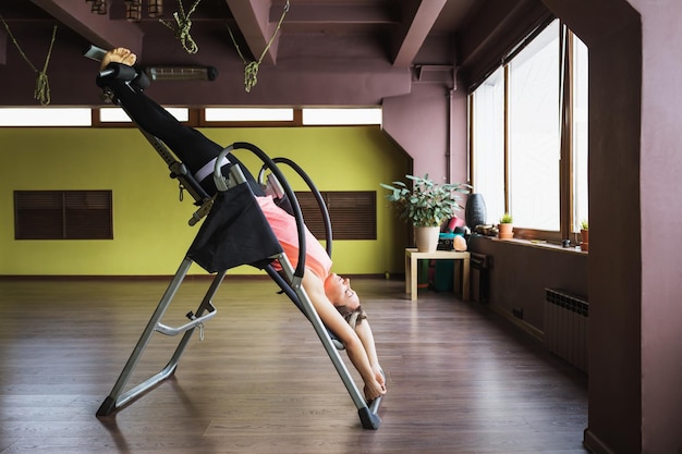 A woman doing inversion therapy hanging upside down on an inversion table