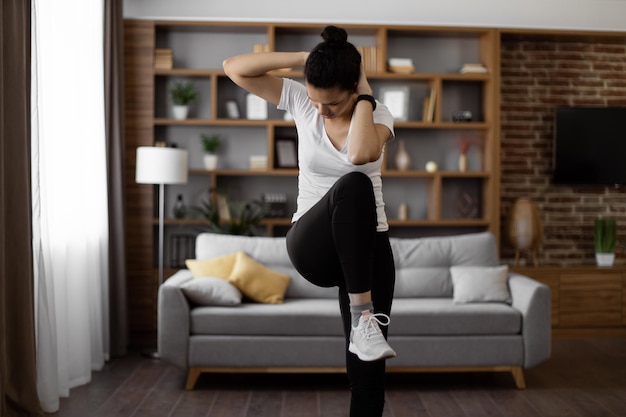 Photo woman doing knee to elbow crunches at living room