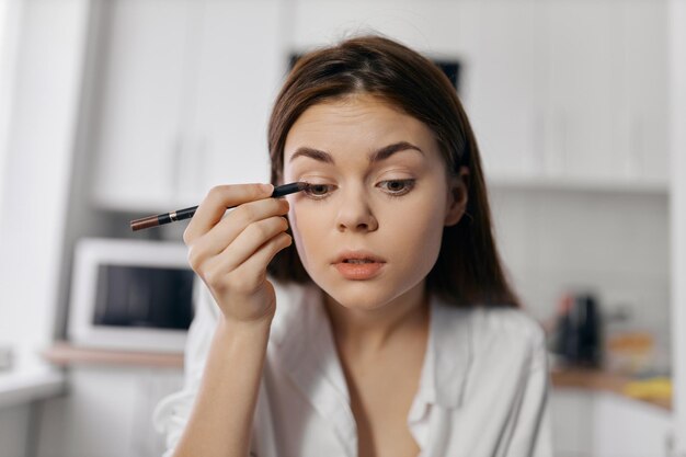 写真 室内のキッチンでメイクをする女性