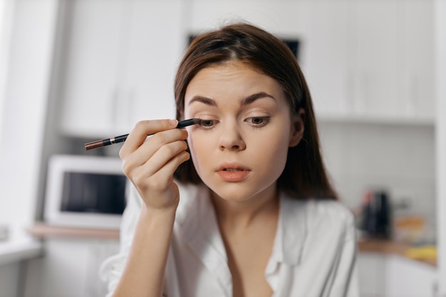 Photo woman doing makeup in the kitchen indoors