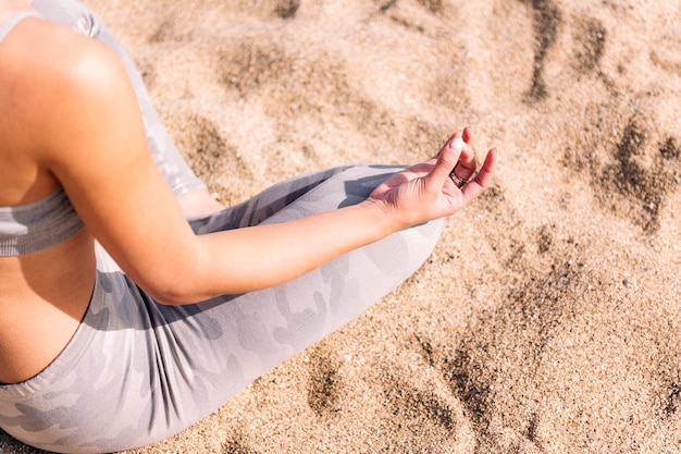 Woman doing meditation sitting on the beach sand