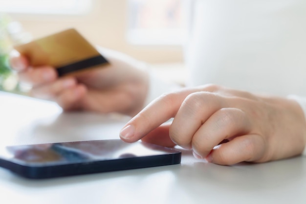 Woman doing online shopping using debit card and mobile Female hands holding credit card over mobi