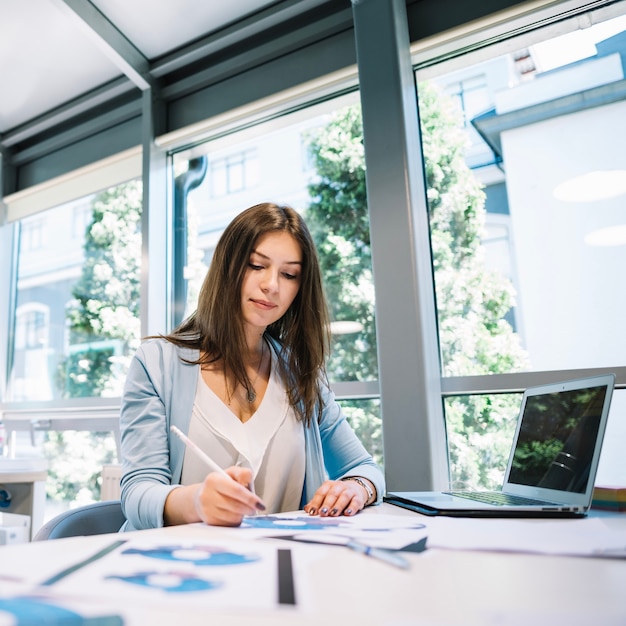 Photo woman doing paperwork at laptop