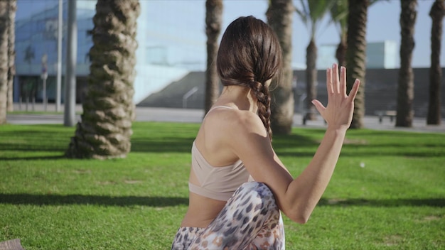 Woman doing seated spinal twist pose on mat Girl performing yoga in park