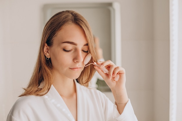 Woman doing self massage with rose quartz face roller